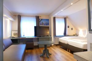 フュッセンにあるアルトシュタット - ホテル ツム ヘヒテンのベッドルーム1室(ベッド1台、デスク、ベッド1台、テーブル付)