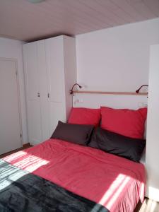 a bedroom with a bed with red sheets and black pillows at Gasthaus Löwen in Unterreichenbach