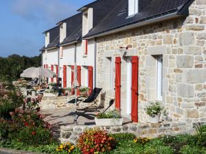 een stenen huis met rode deuren en een patio bij La Ferme de Vur Ven in Saint-Évarzec