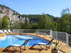 eine Terrasse mit Stühlen und einen Pool mit einem Berg in der Unterkunft Hôtel Restaurant des Grottes du Pech Merle in Cabrerets