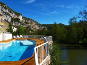 una piscina en una terraza junto a un río en Hôtel Restaurant des Grottes du Pech Merle en Cabrerets