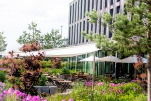 a garden with tables and umbrellas in front of a building at Bader Hotel in Parsdorf