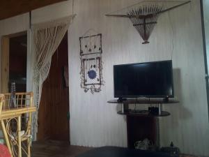TV de pantalla plana en la pared de una habitación en Cabaña La Rustika, en Punta del Diablo