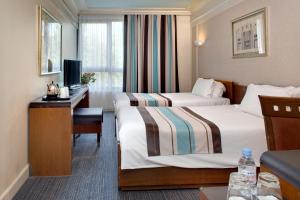 um quarto de hotel com duas camas e uma secretária em Hotel Art Deco Euralille em Lille