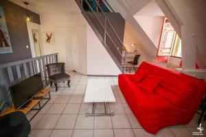 uma sala de estar com um sofá vermelho e uma televisão em DUPLEX CENTRE VILLE 6 personnes (WIFI/PARKING) em Troyes
