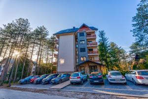 een gebouw met auto's geparkeerd op een parkeerplaats bij Santos Hills Zlatibor in Zlatibor