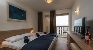 a bedroom with a bed and a television and a balcony at Poseidon The Beach Hotel in Budva