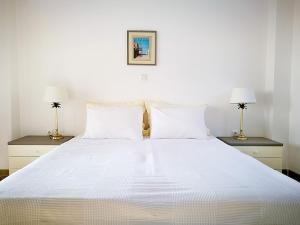 a bedroom with a large white bed with two lamps at Olive Bay Hilltop Apartments Ammouliani in Ammouliani