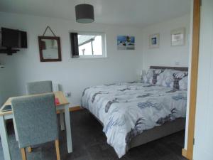 a bedroom with a bed and a table and a chair at Lampay Chalets in Dunvegan