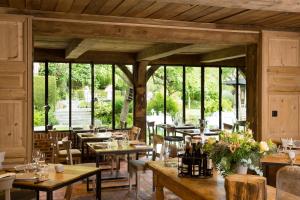 un restaurante con mesas y sillas de madera y ventanas en Auberge de la Source - Hôtel de Charme, Collection Saint-Siméon, en Barneville-la-Bertrand