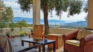 a porch with wicker chairs and a table and a view at Olive Bay Hilltop Apartments Ammouliani in Ammouliani