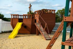 a wooden playground with a yellow slide and a slideintend at InnSeason Resorts Surfside in Falmouth
