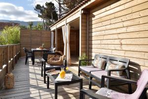 a wooden deck with chairs and tables and a table at Résidence & Hotel U Livanti ECOLABEL in Propriano