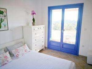 a bedroom with a bed and a blue door at Olive Bay Hilltop Apartments Ammouliani in Ammouliani