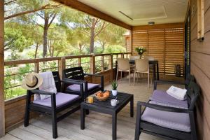 a porch with chairs and a table on a deck at Résidence & Hotel U Livanti ECOLABEL in Propriano