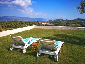 two rocking chairs sitting on top of a field of grass at Olive Bay Hilltop Apartments Ammouliani in Ammouliani