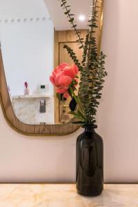 a black vase with a rose in front of a mirror at Rose Bourbon in Paris