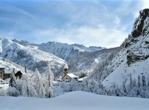 Saint-Dalmas-le-SelvageにあるLa maison basseの遠くの家を持つ雪山