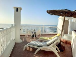 einen Balkon mit einem Tisch, Stühlen und einem Sonnenschirm in der Unterkunft Jack's Apartments & Suites in Essaouira