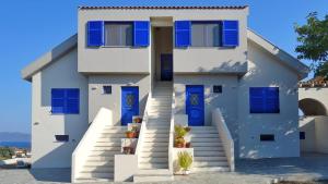 a white house with blue doors and stairs at Olive Bay Hilltop Apartments Ammouliani in Ammouliani