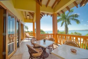 een veranda met tafels en stoelen en uitzicht op de oceaan bij The Villas at Cocoplum in Placencia Village