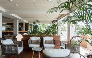 a lobby with chairs and tables and plants at Hotel Maritim in Roses