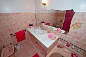 La salle de bains rose est pourvue d'un lavabo et d'un miroir. dans l'établissement Petite Fleur d'Azur, à Cagnes-sur-Mer