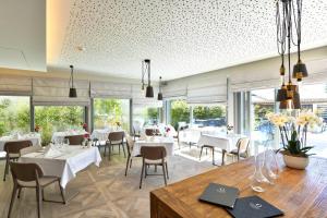 um restaurante com mesas e cadeiras brancas e janelas em Ambassador Boutique Hotel em Nyon