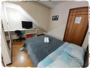 a bedroom with a bed and a desk with a computer at Residencial João Pessoa in Canela