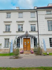 un edificio blanco con una puerta y ventanas marrones en Hotel butikowy Pałac Jabłonna, en Jabłonna