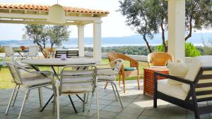 a table and chairs on a patio with a view at Olive Bay Hilltop Apartments Ammouliani in Ammouliani