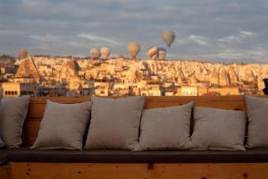 a couch with a view of a city with hot air balloons at Cappadocia Cave Rooms in Göreme