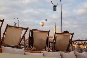 een groep stoelen op een balkon met luchtballonnen bij Cappadocia Cave Rooms in Goreme