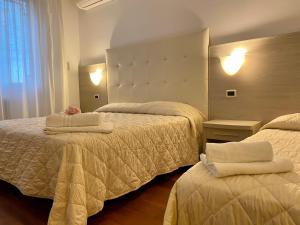 een hotelkamer met twee bedden met handdoeken erop bij Villa Alda Suites & Rooms in Cervia