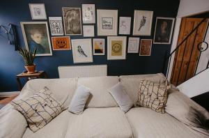 a couch in a living room with pictures on the wall at Unique, cosy, Lake District artist hideaway - 5 bd in Millom