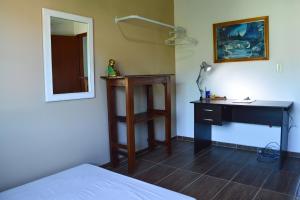 1 dormitorio con escritorio, 1 cama y espejo en Mozamba Surf House, en Florianópolis