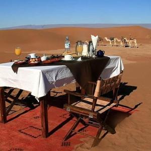 einen Tisch in der Wüste mit Zebras im Hintergrund in der Unterkunft berber sahara in Zagora