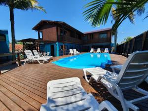 a deck with lounge chairs and a swimming pool at Pousada Doce Mar in Guarda do Embaú