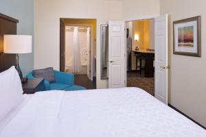 ein Schlafzimmer mit einem weißen Bett und einem blauen Stuhl in der Unterkunft Staybridge Suites Indianapolis-Fishers, an IHG Hotel in Fishers