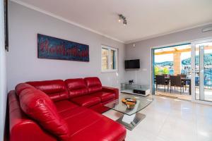 een rode leren bank in een woonkamer met een tafel bij Luxury Apartment Marina View No 1 in Vela Luka