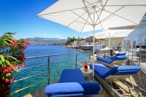 einen Balkon mit blauen Stühlen, einem Sonnenschirm und Wasser in der Unterkunft Amore Rentals - Villa del Maggiore in Sorrent