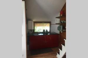 a kitchen with red cabinets and a window at Gite bien-être hammam et jacuzzi ,sauna in La Grotte