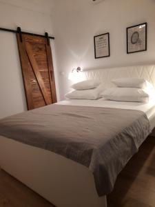 a bedroom with a large white bed with a wooden door at Private Accomodation Linda in Dubrovnik