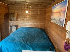 a bedroom with a blue bed in a wooden room at Chalet - B&B de Koog in Uitgeest