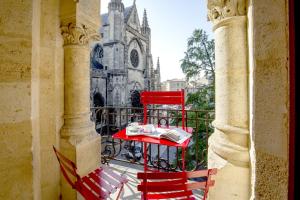 une table et des chaises rouges sur un balcon en face d'une église dans l'établissement Place Saint Michel Apartment, à Bordeaux