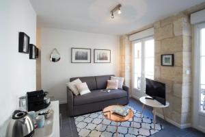 ein Wohnzimmer mit einem Sofa und einem TV in der Unterkunft Appartement Bordeaux Centre Historique in Bordeaux