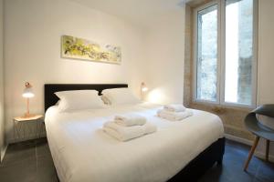 ein Schlafzimmer mit einem großen weißen Bett mit Handtüchern darauf in der Unterkunft Appartement Bordeaux Centre Historique in Bordeaux