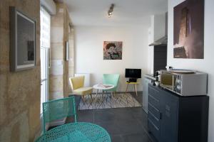 eine Küche mit Stühlen, einem Tisch und einer Mikrowelle in der Unterkunft Appartement Bordeaux Centre Historique in Bordeaux
