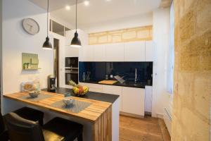 eine Küche mit weißen Schränken und einer Arbeitsplatte in der Unterkunft Appartement Luxe - La Devise in Bordeaux