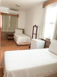 a bedroom with two white beds and a window at Millian Hotel in Jundiaí